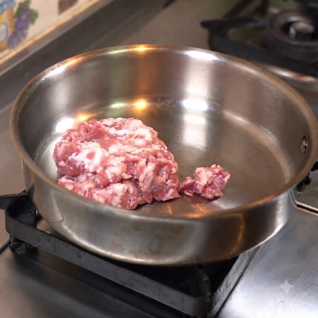 Carne picada presionada de forma plana en una sartén de acero inoxidable para cocinarla.