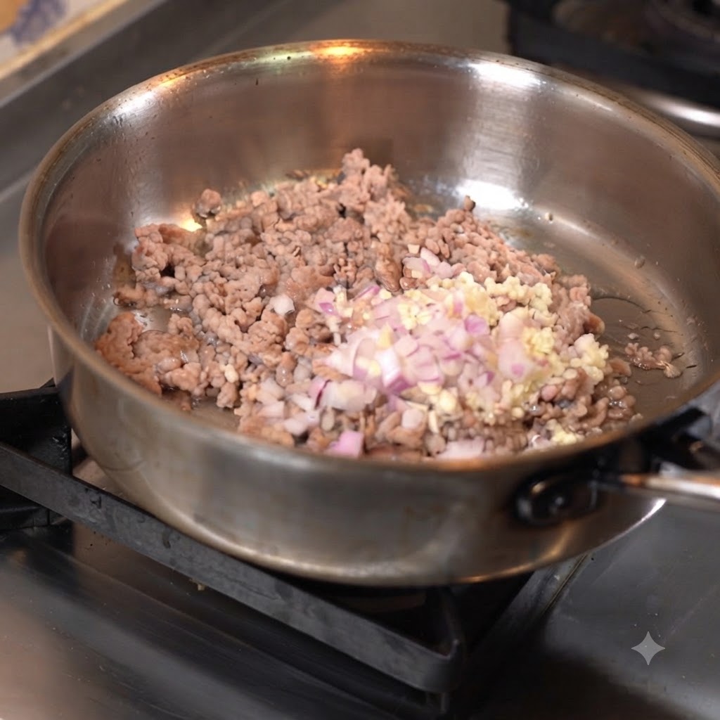 Carne picada siendo salteada en una sartén con ajo picado y cebolla.