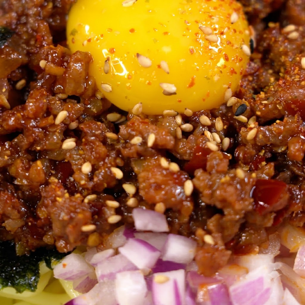 Salsa siendo vertida y removida con la carne picada dorada en una sartén.