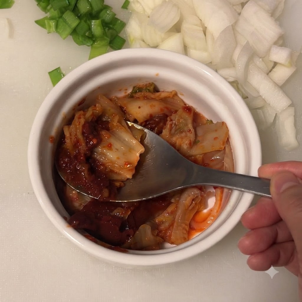Salsa de soja clara siendo añadida al cuenco con kimchi y pasta de ají coreano.