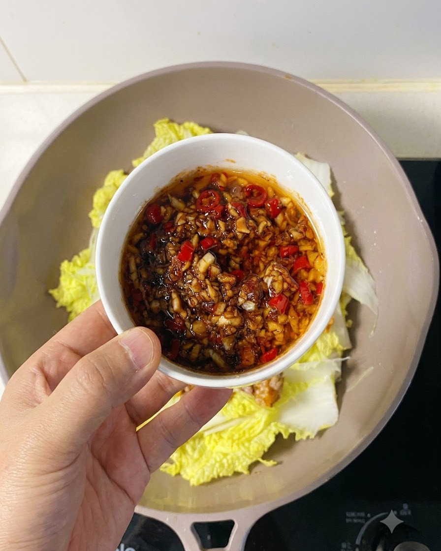 Salsa sabrosa de ajo y chile siendo esparcida generosamente sobre la carne de vieira dispuesta.