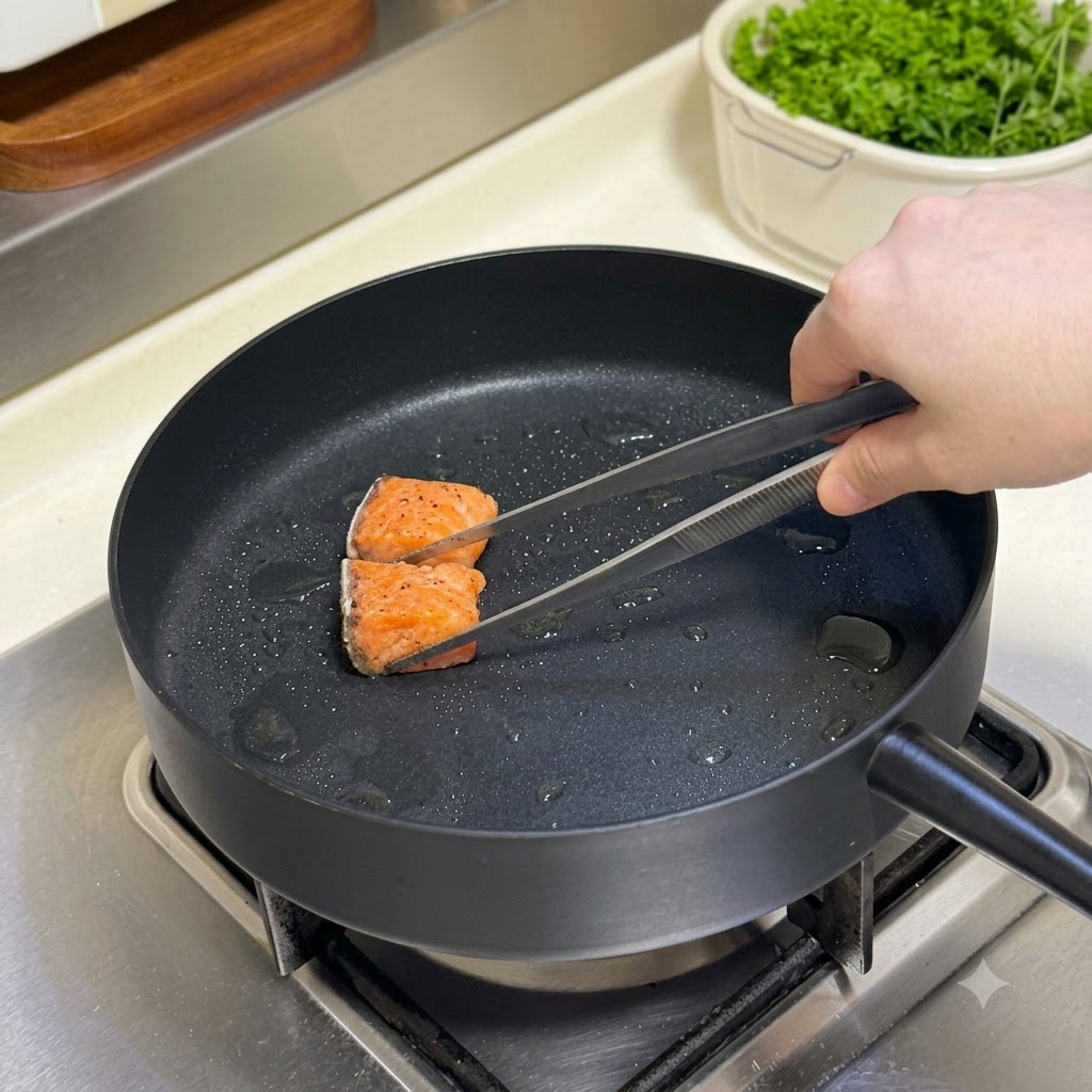 Cubos de salmón sazonados siendo girados en una sartén caliente con unas tenazas.