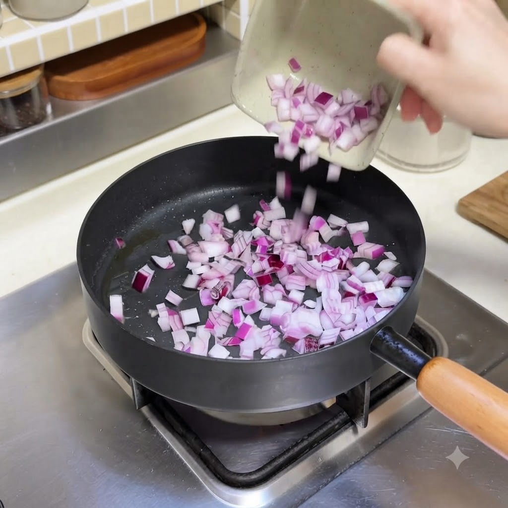 Cebollas rojas picadas siendo vertidas desde un plato pequeño a una sartén caliente.
