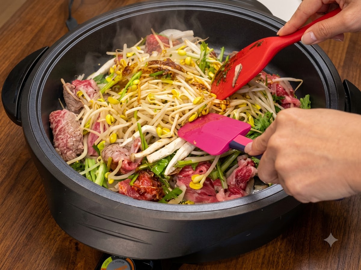 Dos espátulas mezclando y salteando ingredientes dentro de una sartén caliente mientras se incorpora más salsa.