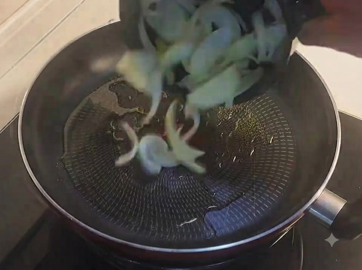 Cebollas amarillas en rodajas cayendo en una sartén negra con aceitecite: 1.