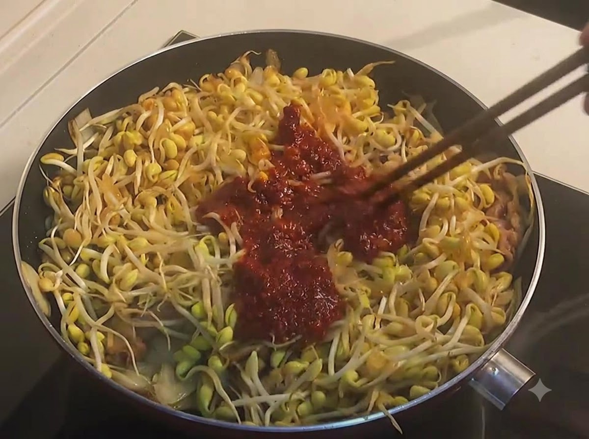Palillos mezclando brotes de soja amarilla y ternera con una salsa picante roja, oscura y espesa en una sarténcite: 1.