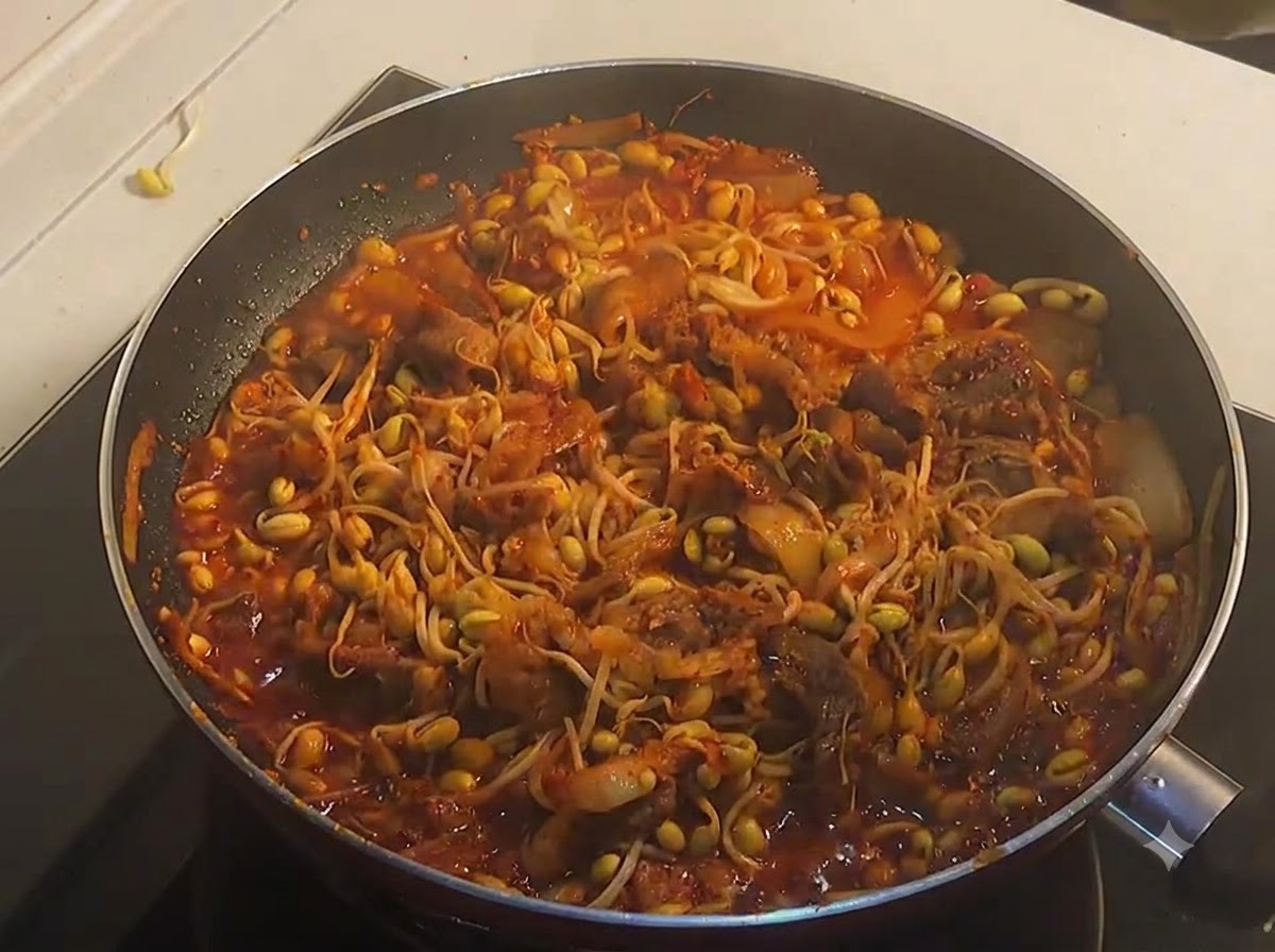 Una sartén llena de ternera picante y brotes de soja amarilla completamente cocinados y burbujeantes en una rica salsa rojacite: 1.