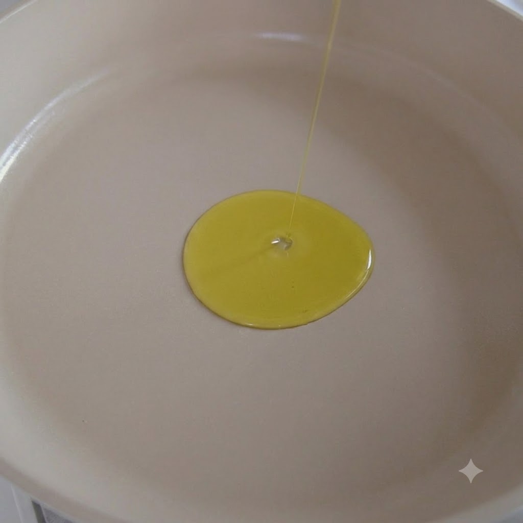 Aceite de oliva siendo vertido en una sartén blanca con ajo sofriéndose dentro.
