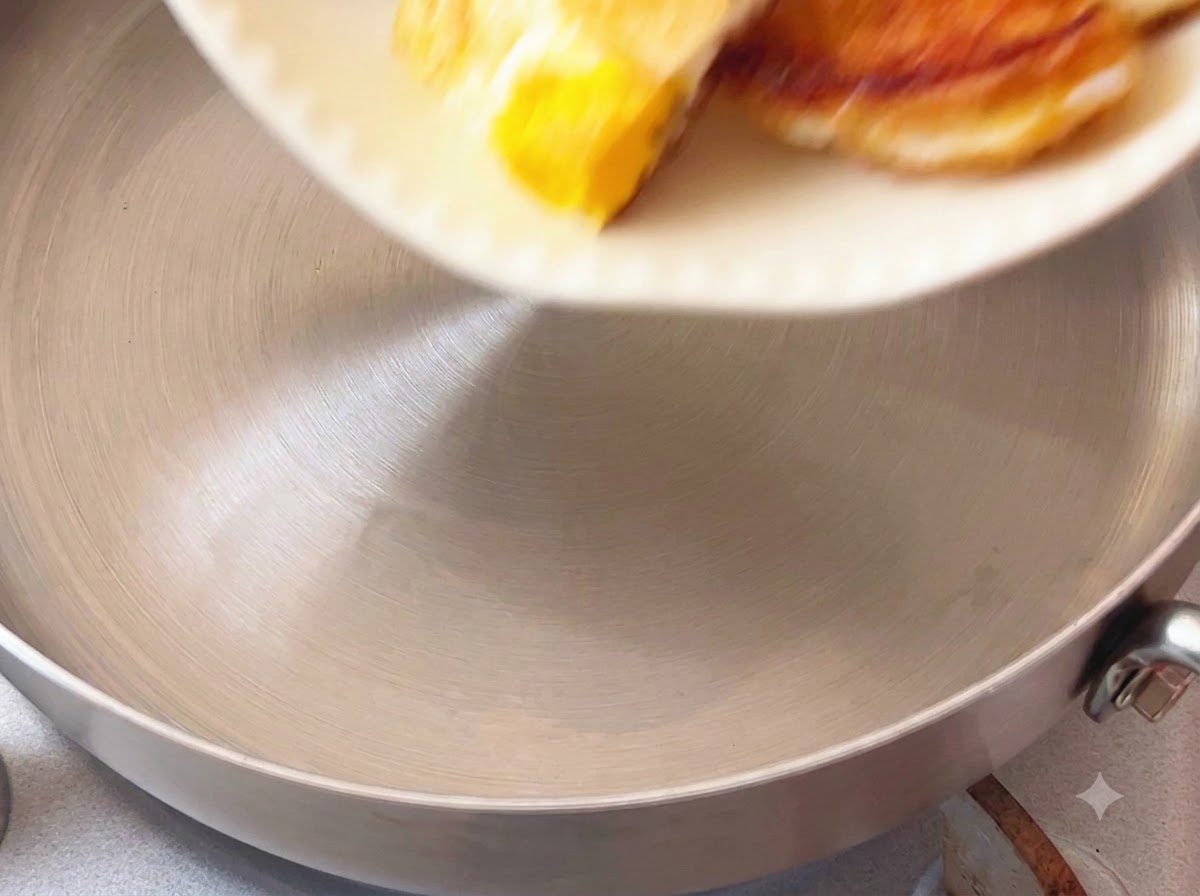 Trozos de huevo frito colocados en una olla de cocina desde un plato blanco.