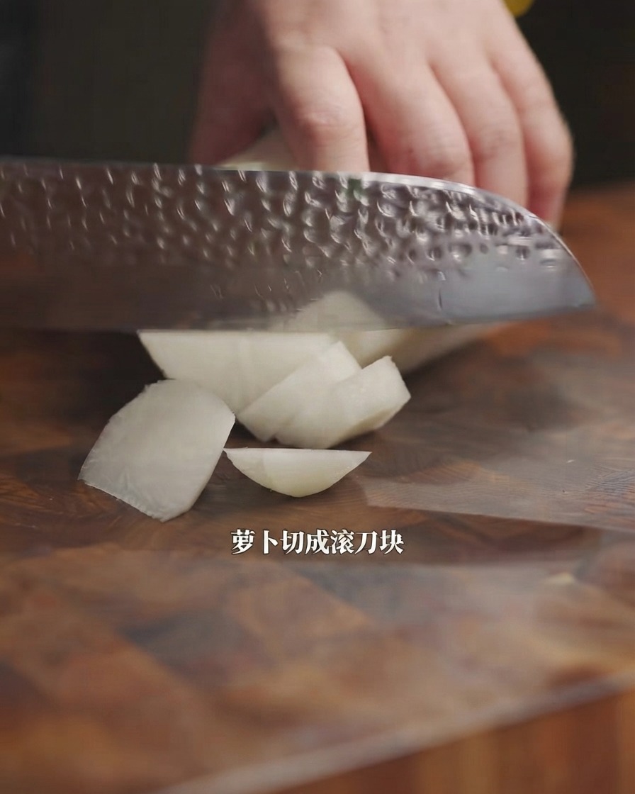 Un cuchillo de cocina cortando un rábano blanco en trozos sobre una tabla de madera.