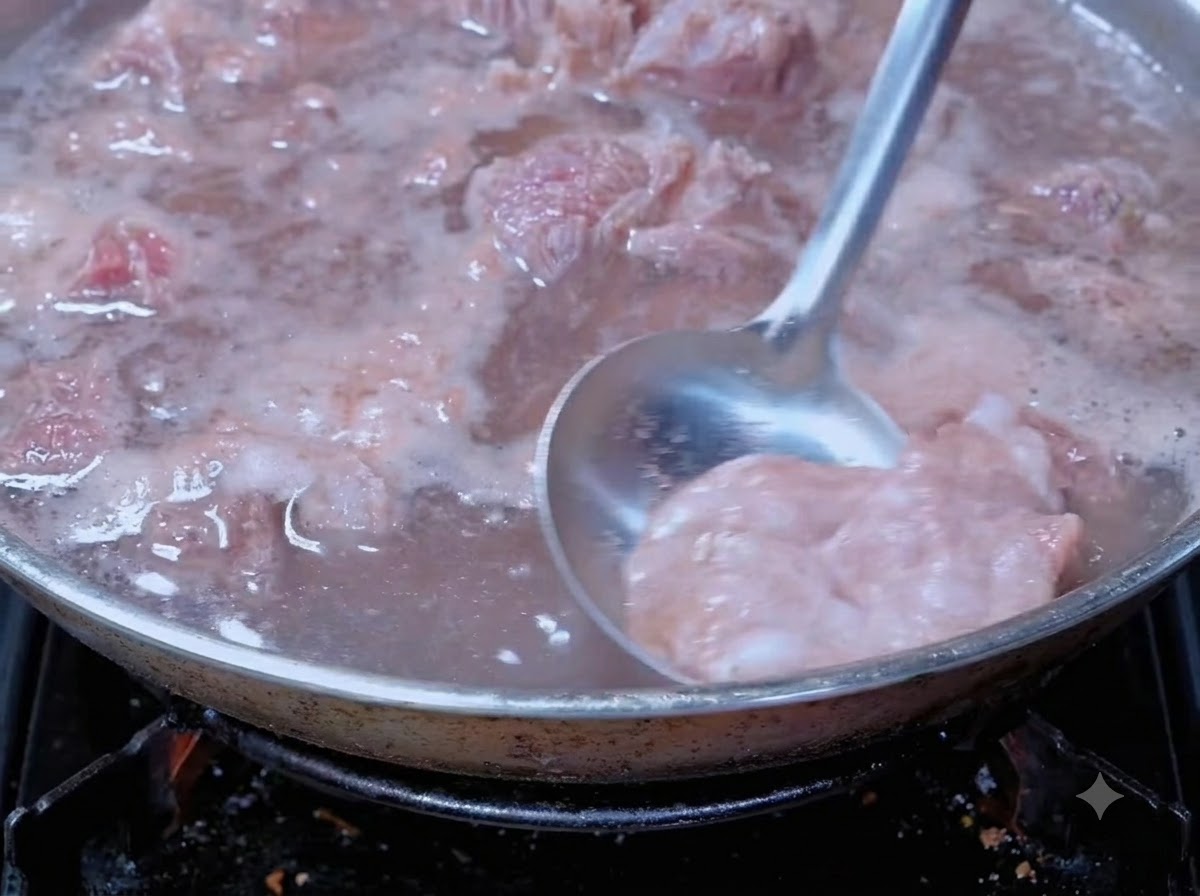 Un cucharón eliminando la espuma de sangre de la carne hirviendo en una olla de cocción.