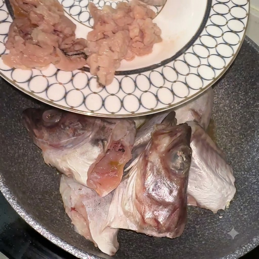 Trozos y cabezas de abadejo siendo transferidos desde un plato estampado hacia una sartén.