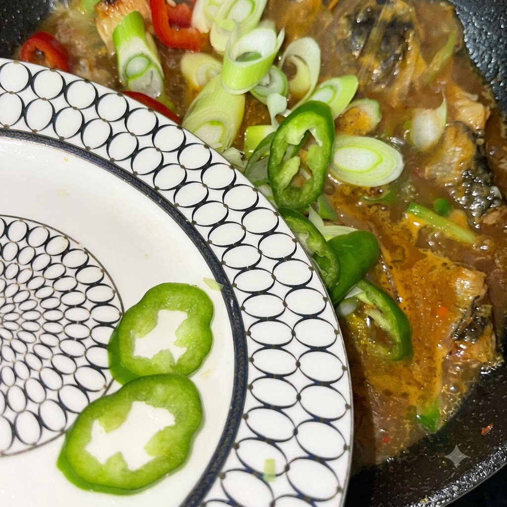Cebollas verdes y chiles rojos y verdes recién cortados siendo vertidos desde un plato estampado hacia la olla en ebullición.
