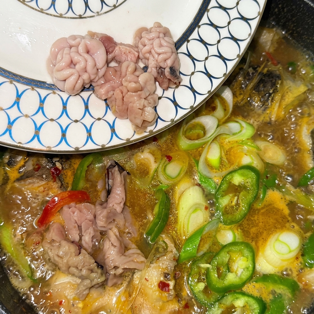 Lecharas y huevas de pescado frescas siendo transferidas desde un plato estampado directamente a la sopa burbujeante.