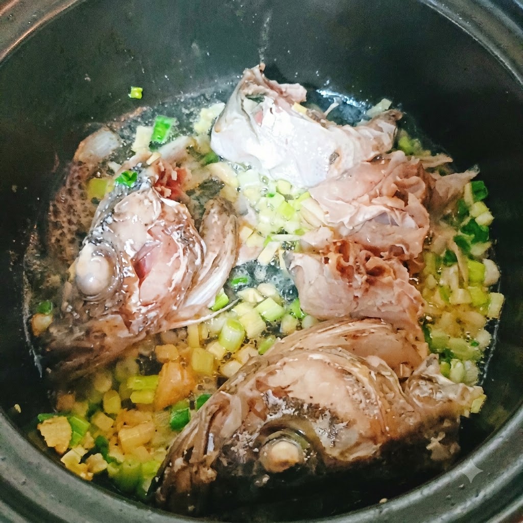 Trozos de pescado abadejo y cabeza friéndose en una olla con aromáticos picados.