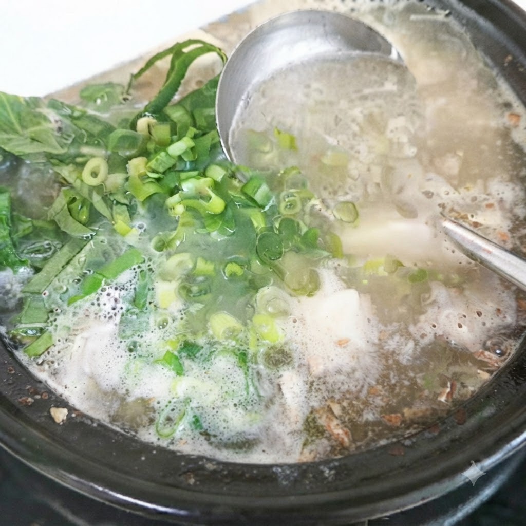 Hojas de perilla fresca y cebollas verdes picadas siendo añadidas a la olla de sopa terminada.