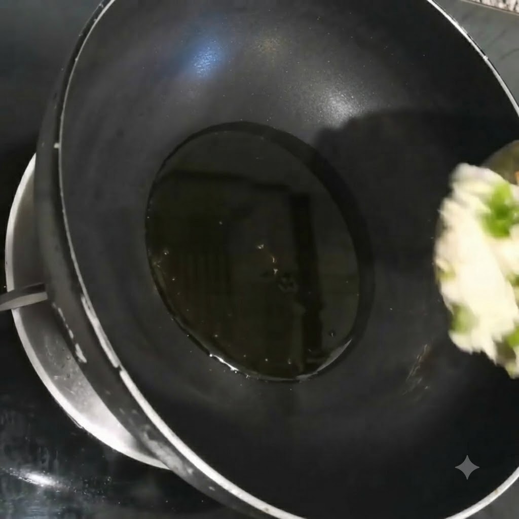 Cebollinos picados, ajo y cilantro chisporroteando en aceite caliente dentro de un wok negro.