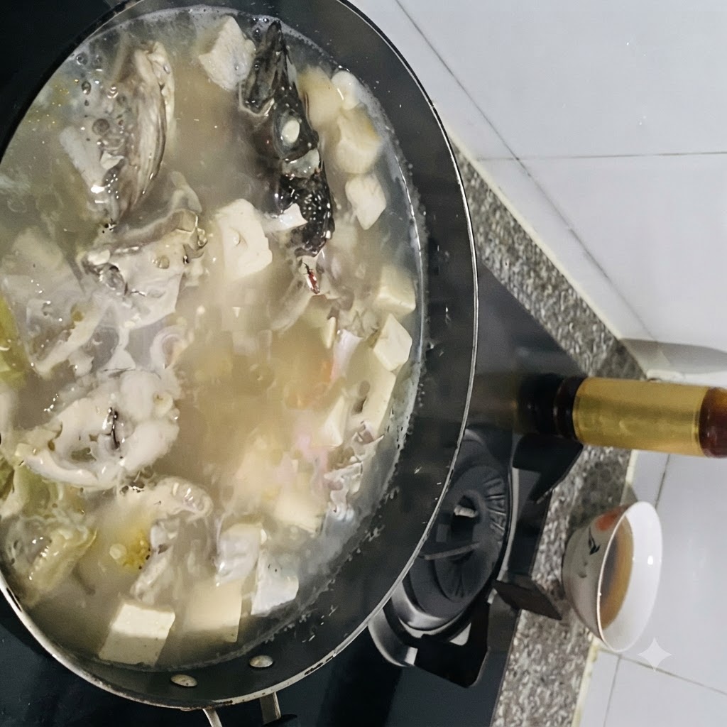 Condimentos siendo añadidos a una olla hirviendo de sopa de pescado con tofu.