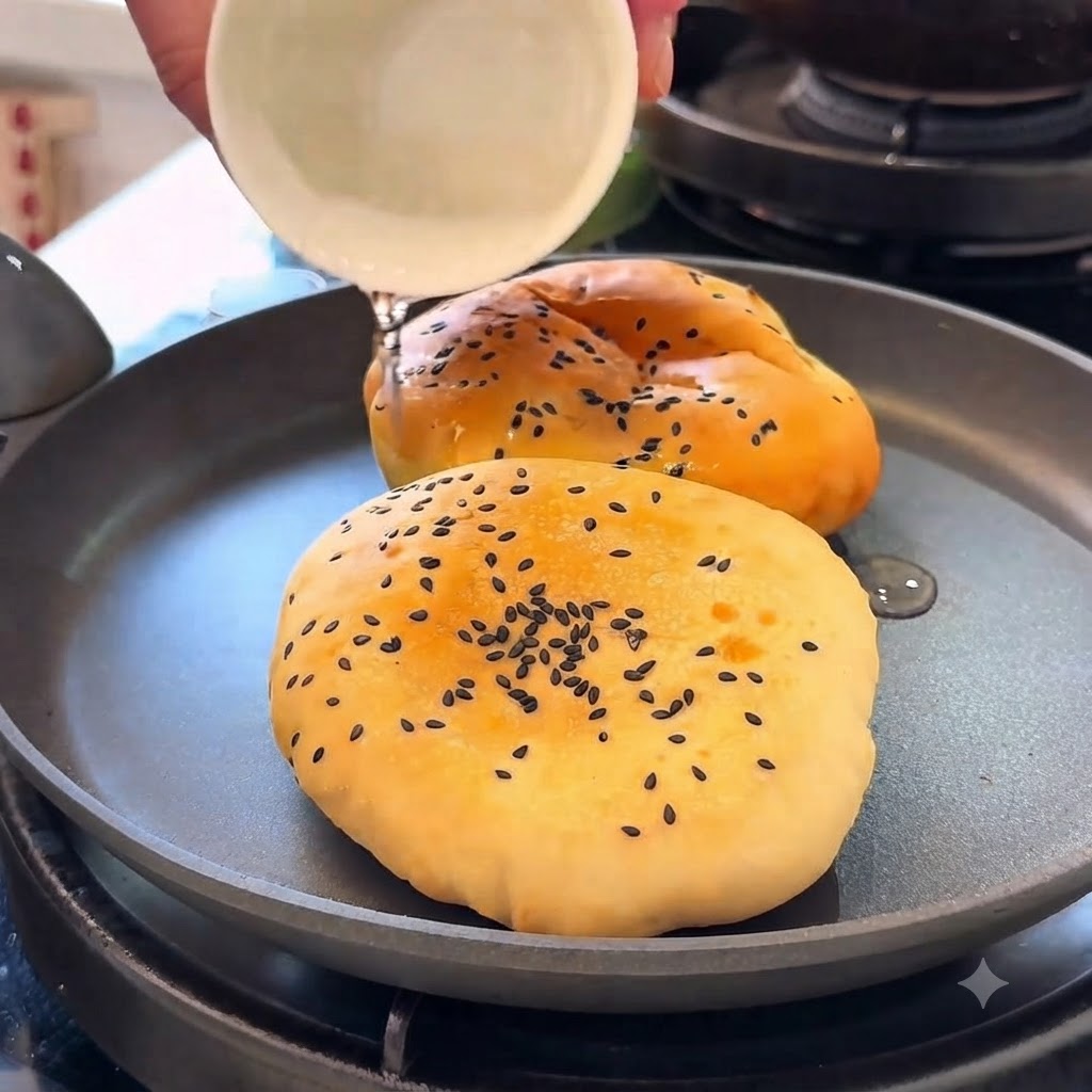 Panes de hamburguesa calentándose en una sartén con agua mientras están cubiertos.