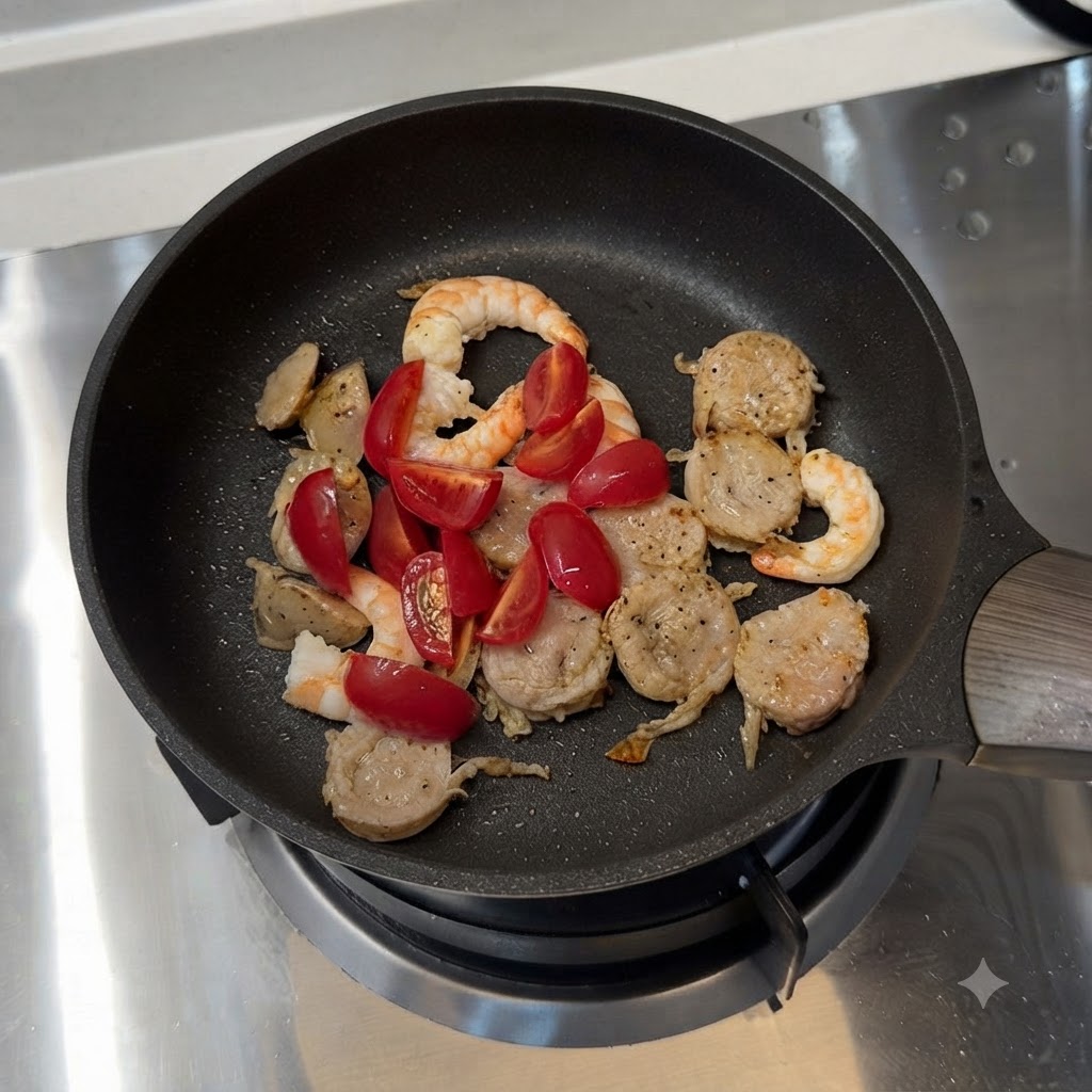 Tomates cherry y pimiento verde en rodajas mezclados con salchicha y camarones en una sartén.