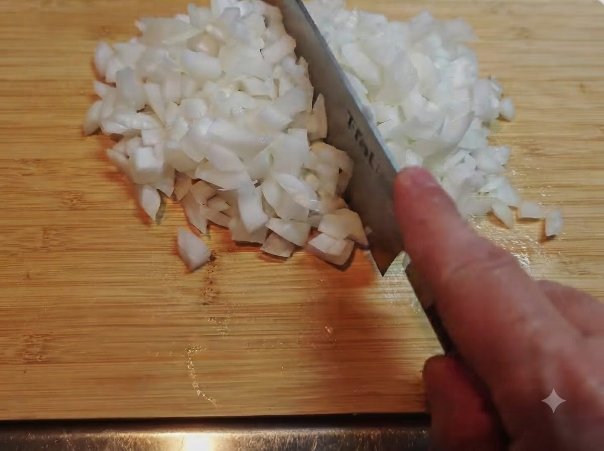 Un montón de cebollas blancas finamente picadas con un cuchillo en una tabla de cortar de bambú.
