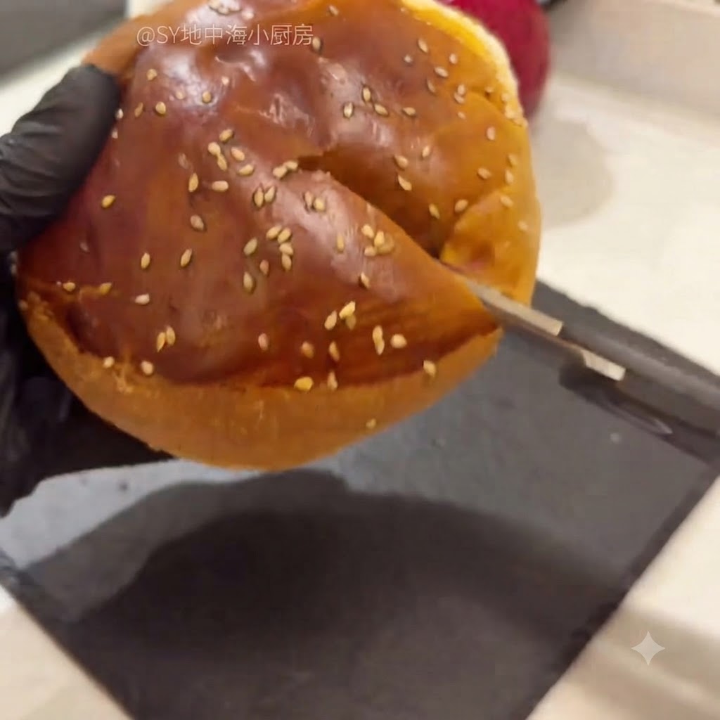 Un pan de hamburguesa abierto con tijeras de cocina, mostrando la miga interior suave siendo retirada.