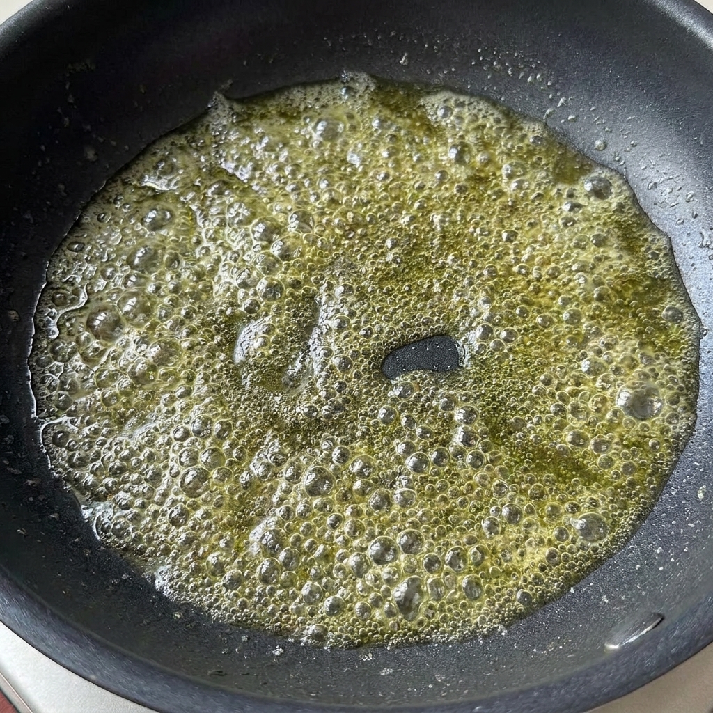Salsa de soja ligera y pasta de tomate añadidas a la mantequilla derretida burbujeante en una sartén.