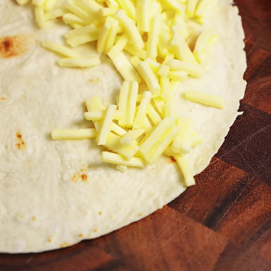 Relleno de ternera cocida y queso mozzarella siendo dispuesto en una mitad de una tortilla de harina plana.