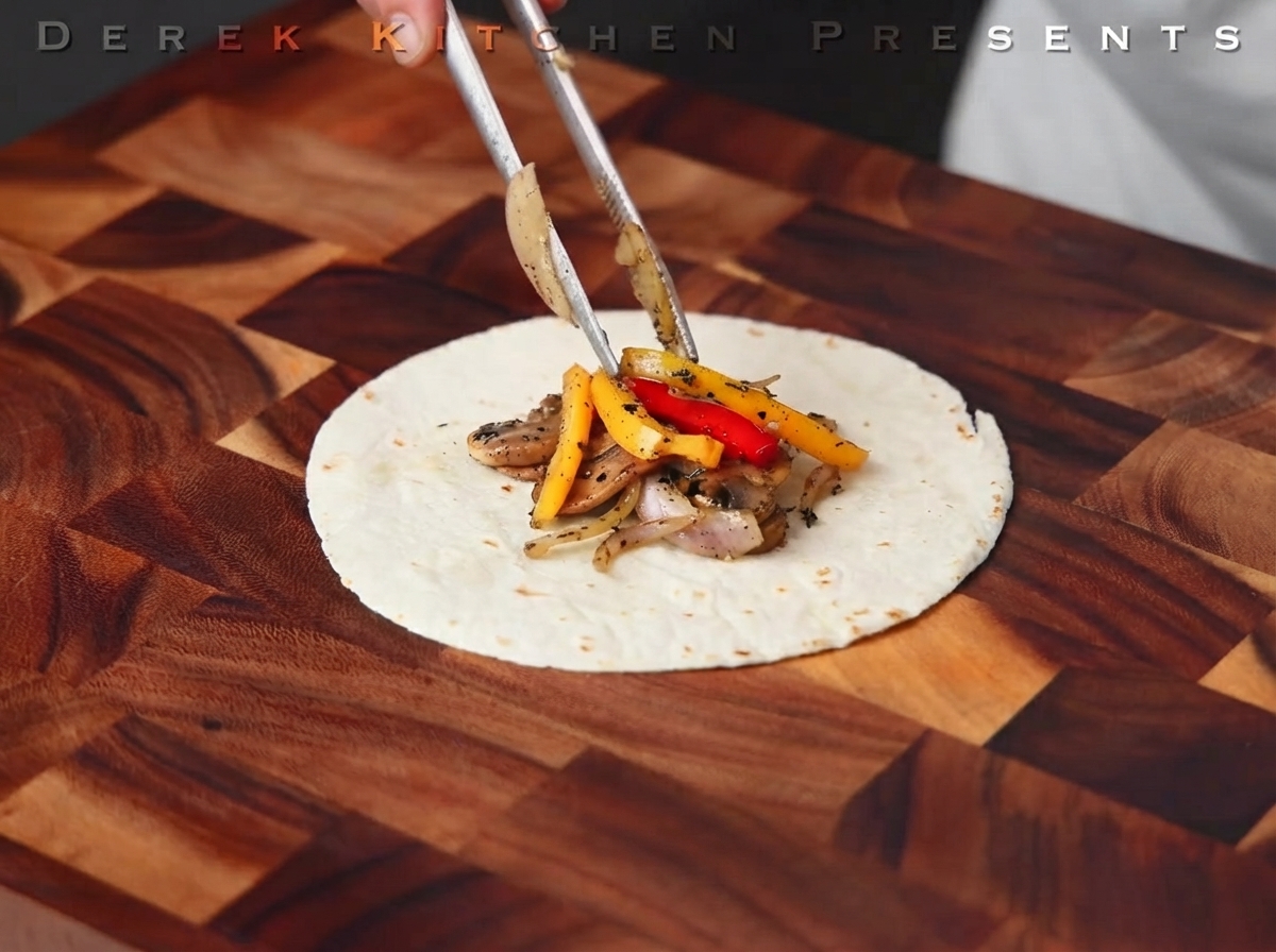 Filete cocido siendo cortado en tiras sobre una tabla de madera.