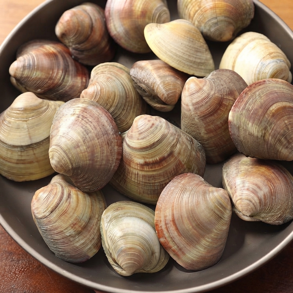 Almejas frescas presentadas en un plato oscuro.