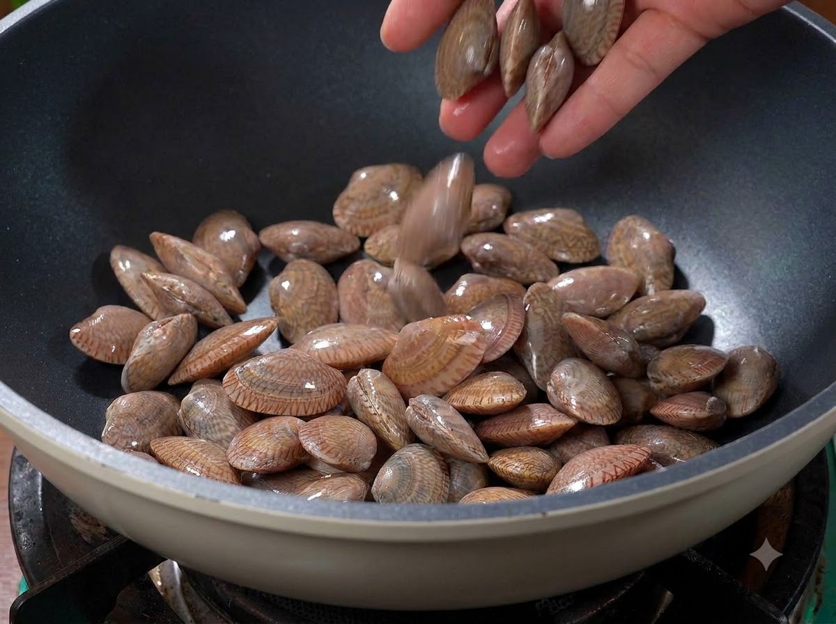 Almejas siendo arrojadas a un wok seco y caliente en la estufa.