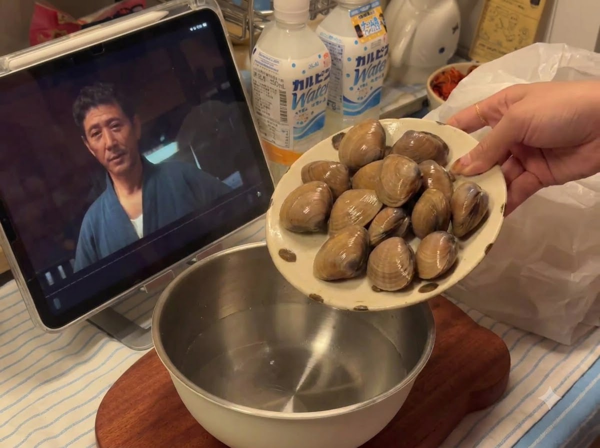Almejas frescas siendo vertidas desde un plato en un bol de metálico que contiene agua.