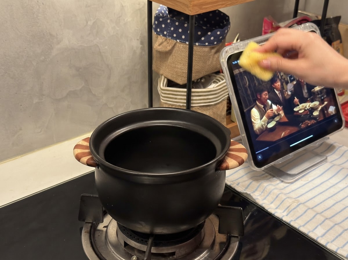 Una pequeña olla de cerámica negra situada sobre el quemador de una estufa de gas.