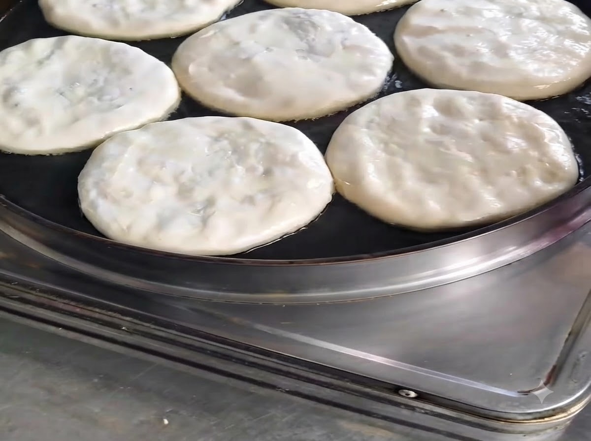 Varias empanadas de carne cocinándose en una sartén, rociadas con un hilo de aceite.