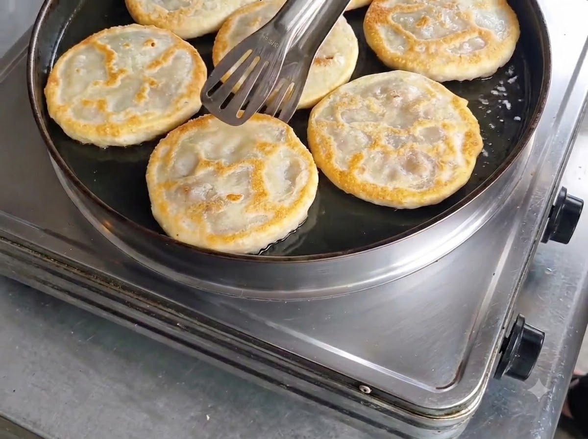 Empanadas de carne doradas y cocinadas siendo comprobadas con pinzas antes de retirarlas de la sartén.