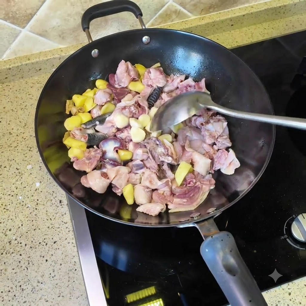 Dientes de ajo y chiles secos siendo arrojados al wok con el pollo y los trozos de jengibre.