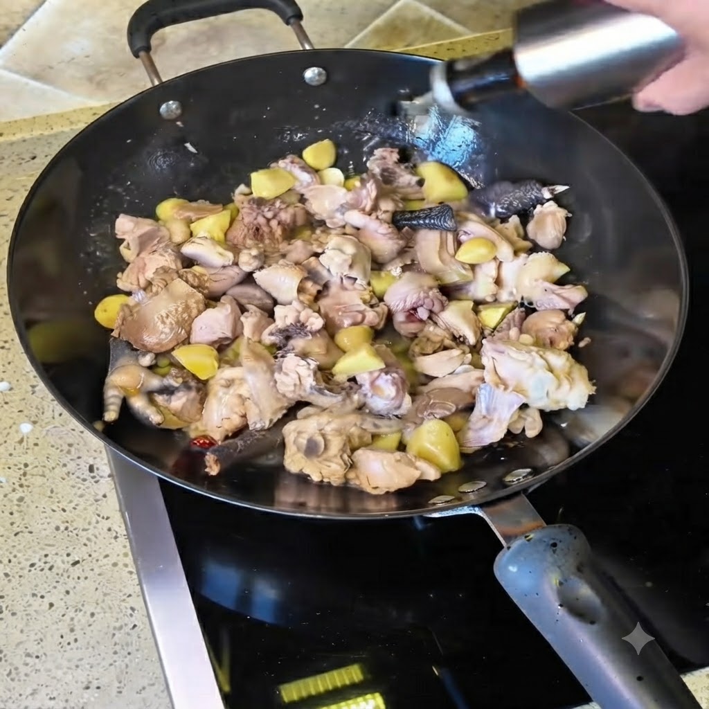 Vino amarillo siendo vertido desde una botella al wok lleno de trozos de pollo en salteado.