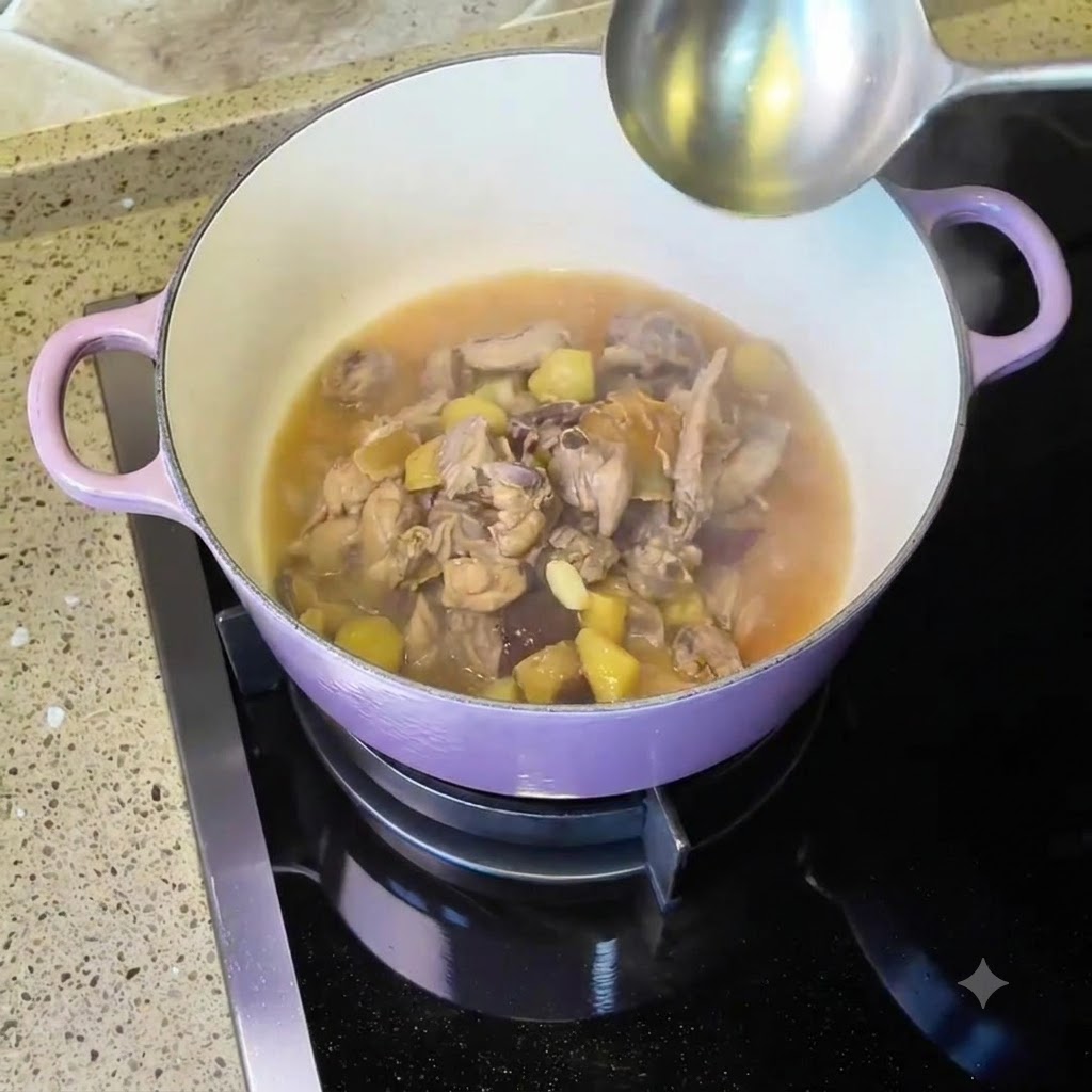 Pollo y sopa cociéndose a fuego lento dentro de una olla holandesa morada en la estufa con un cucharón cerca.
