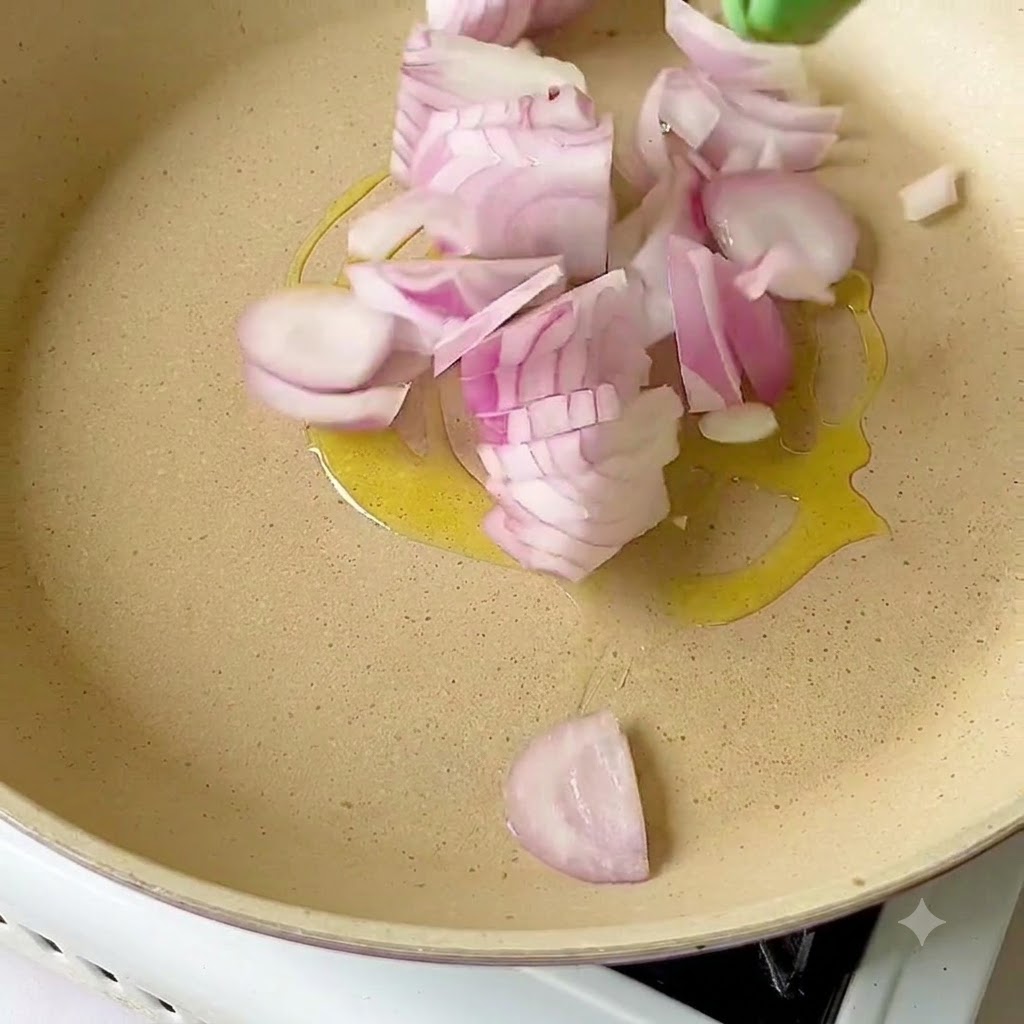 Cebollas rojas cortadas en rodajas chisporroteando en aceite de oliva dentro de una sartén.