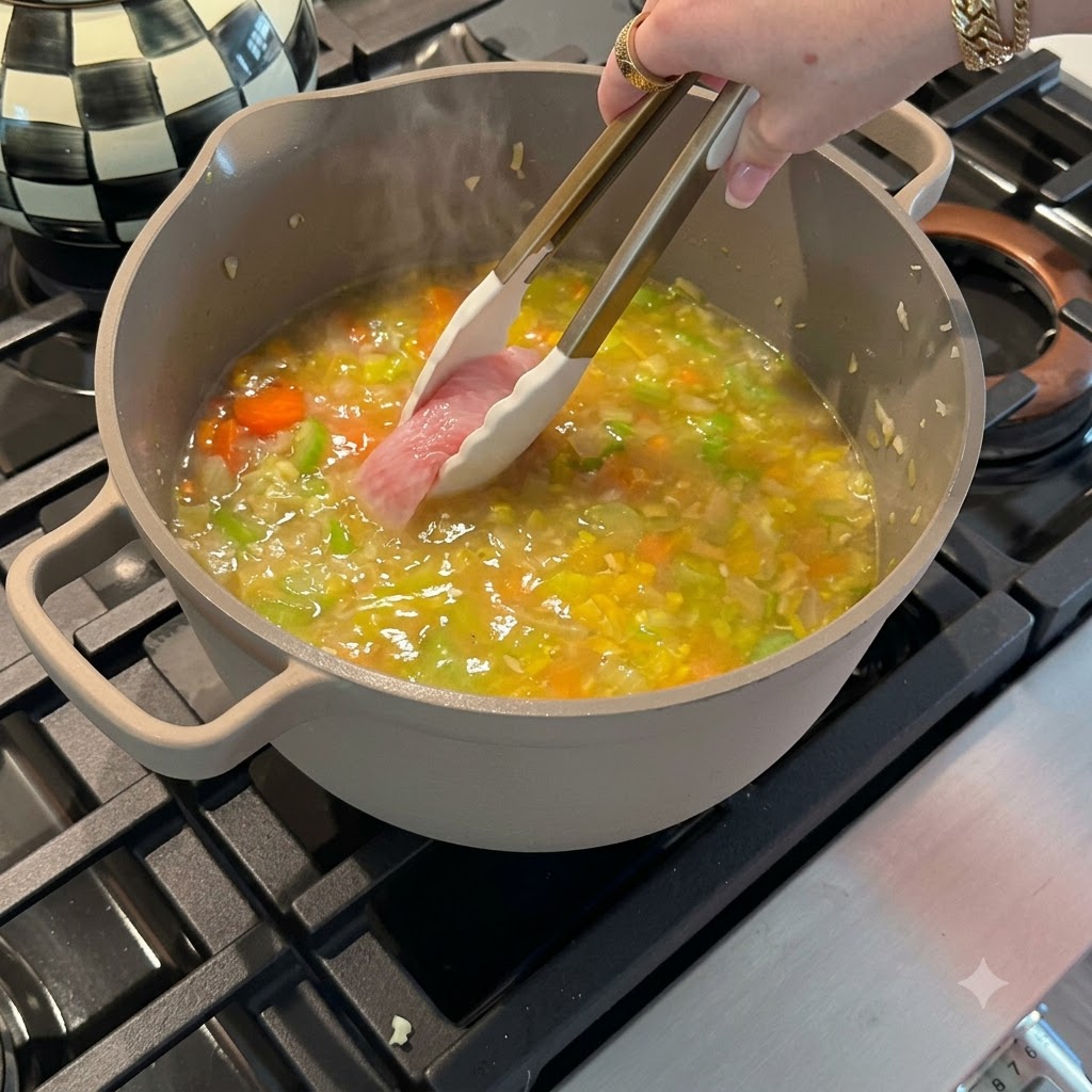 Pechugas de pollo crudas colocándose en una olla con caldo de verduras burbujeante usando pinzas de silicona.