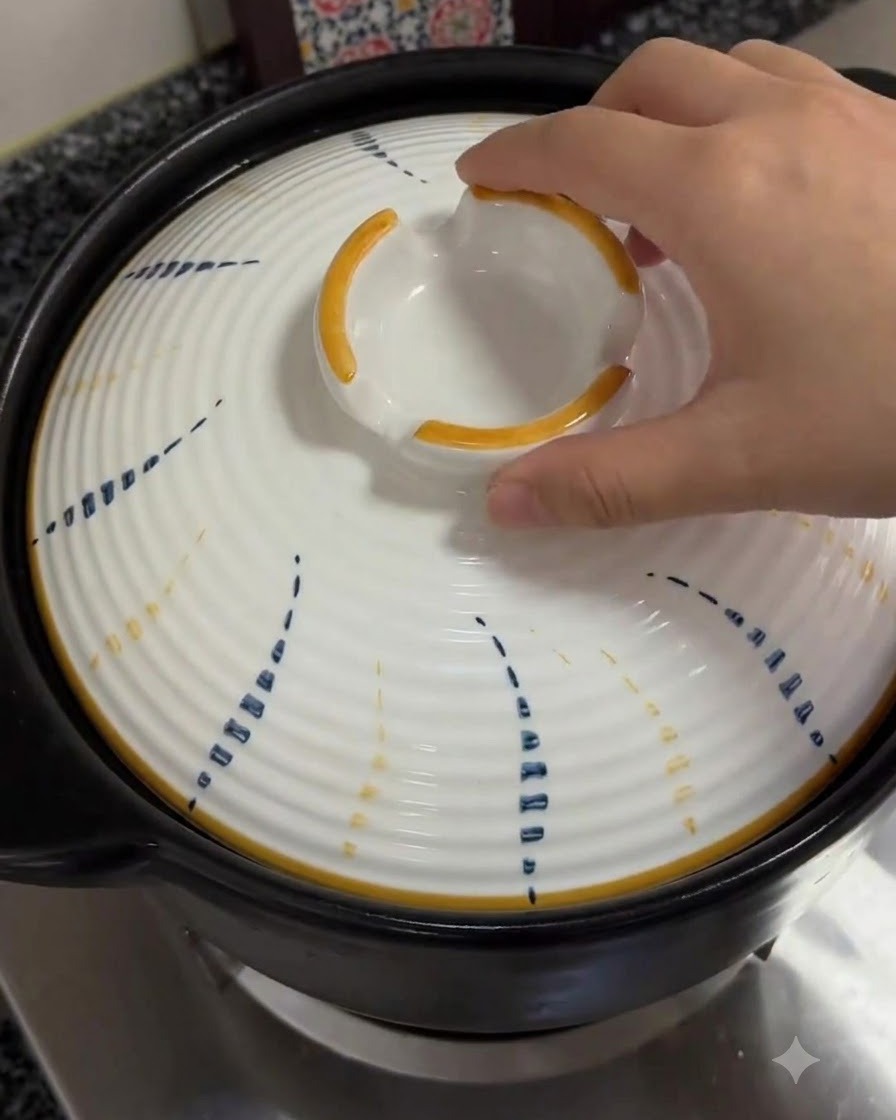 Una mano colocando la tapa blanca estampada de nuevo sobre la olla de barro.