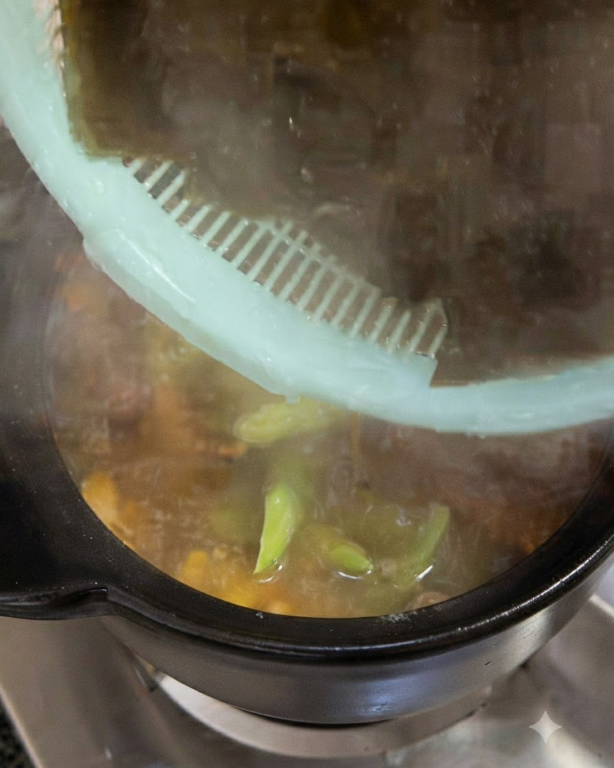 Trozos grandes de alga kelp verde oscuro siendo añadidos a la olla desde un colador verde.