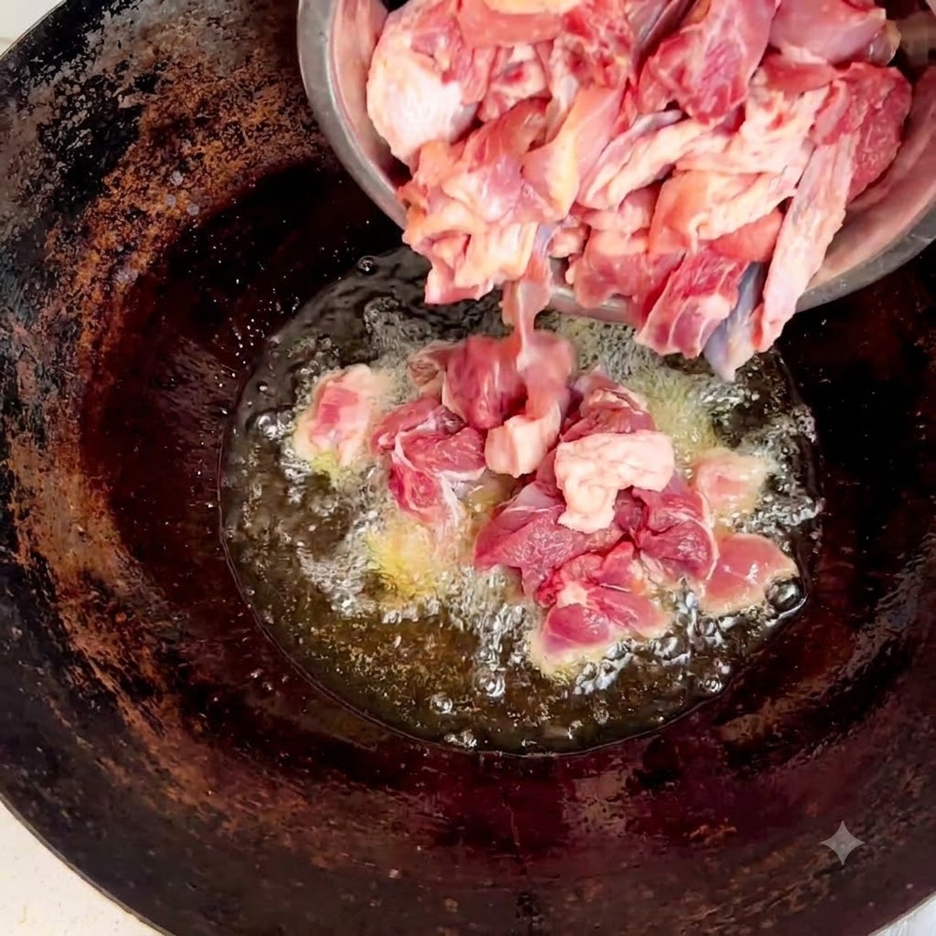 Trozos de pollo crudo cayendo desde un bol de acero al wok con aceite y jengibre.