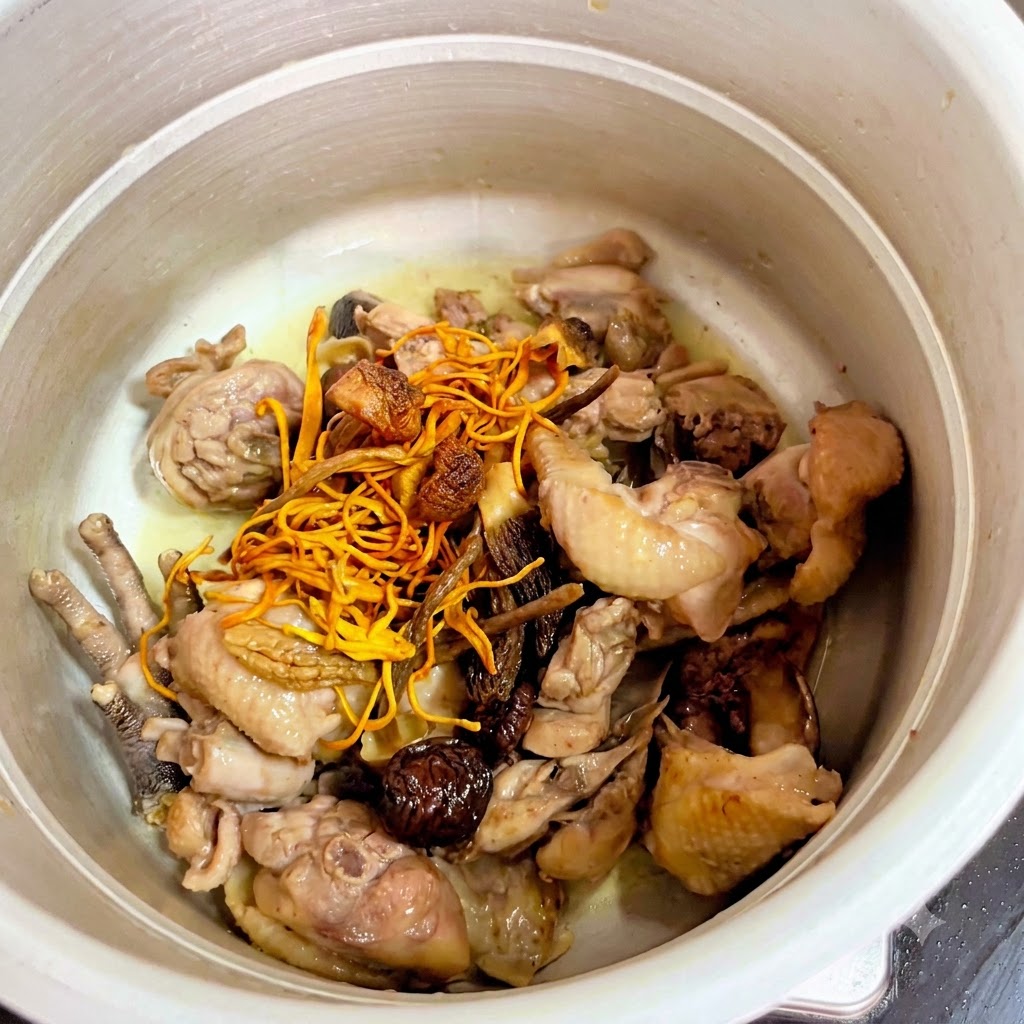 Setas secas y flores amarillas de cordyceps colocadas sobre el pollo en la olla a presión.