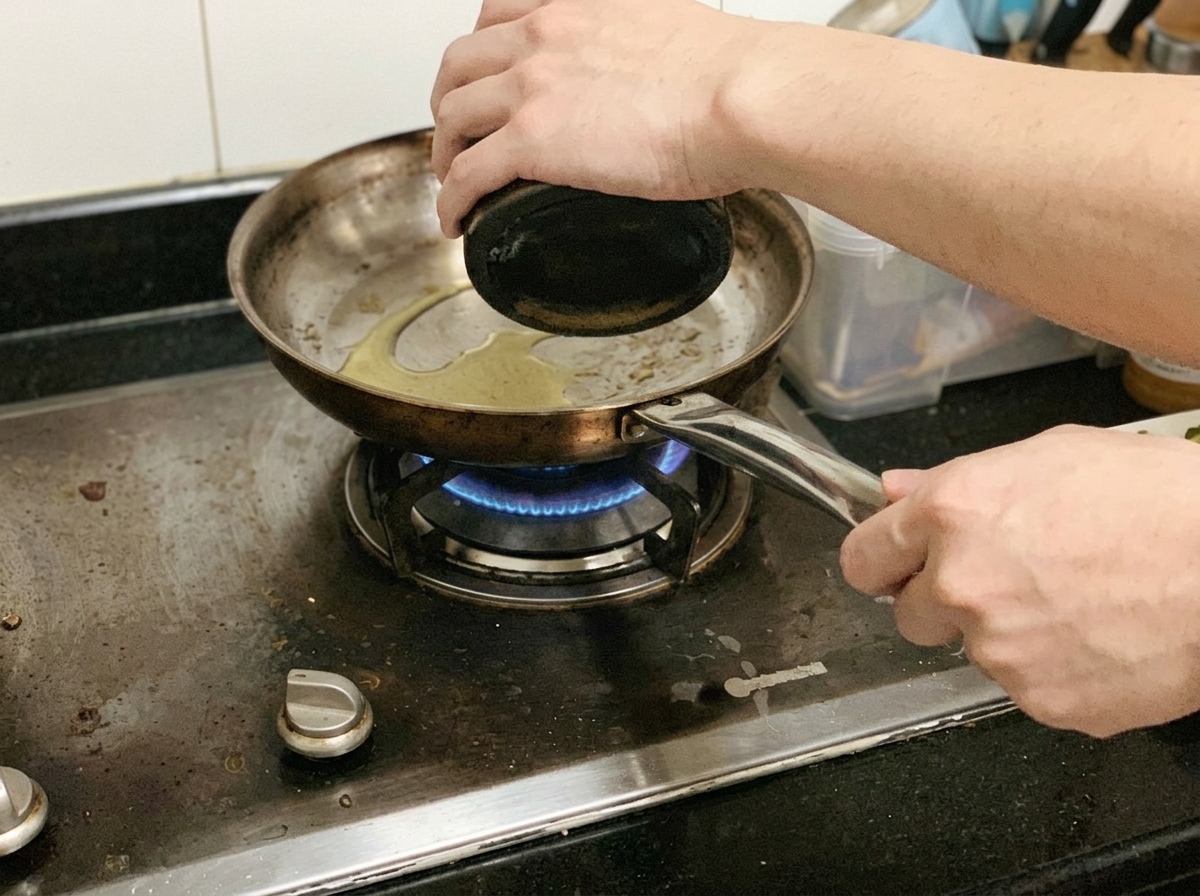 Trozos de pechuga de pollo friéndose y sazonándose con pimienta negra en una sartén en la estufa.