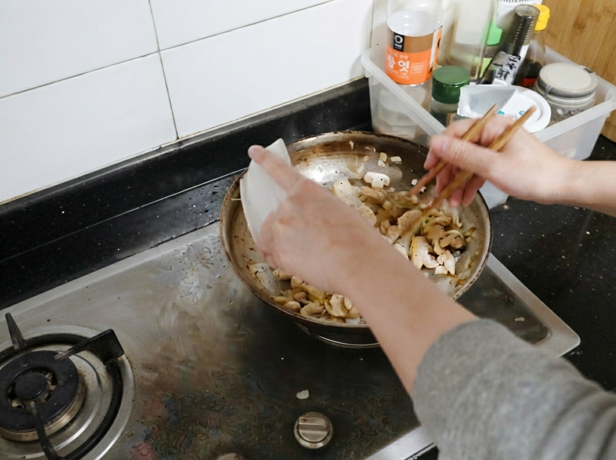 Trozos de pollo cocidos siendo incorporados de nuevo a la sartén con champiñones y cebollas.