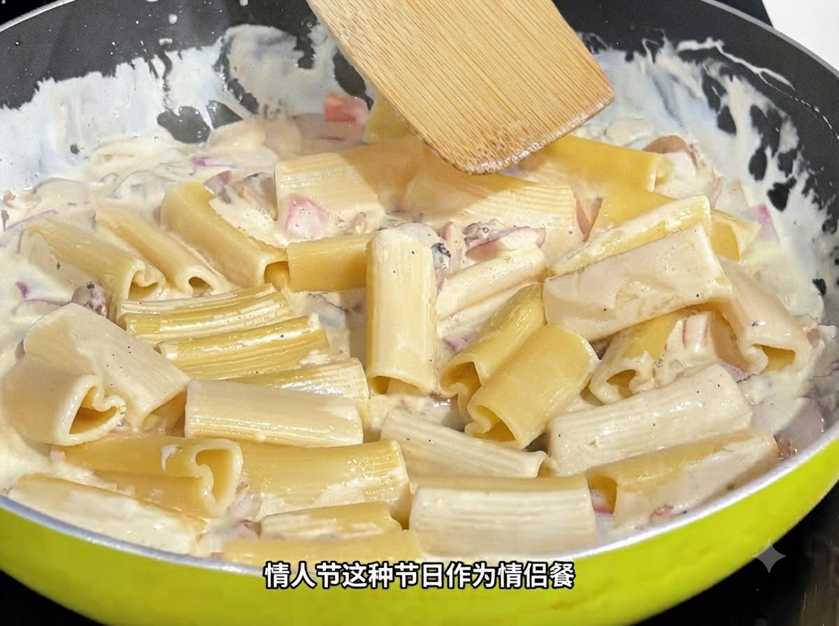 Una espátula de madera revolviendo pasta en forma de corazón en una salsa cremosa dentro de un sartén.