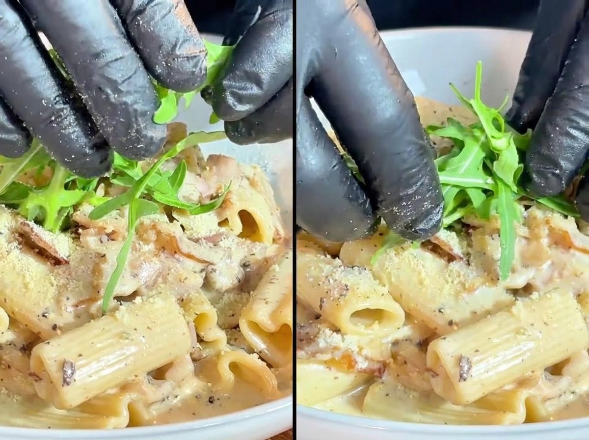 Hojas de rúcula verde fresca y tomates cherry siendo colocados cuidadosamente como guarnición sobre la pasta cremosa.