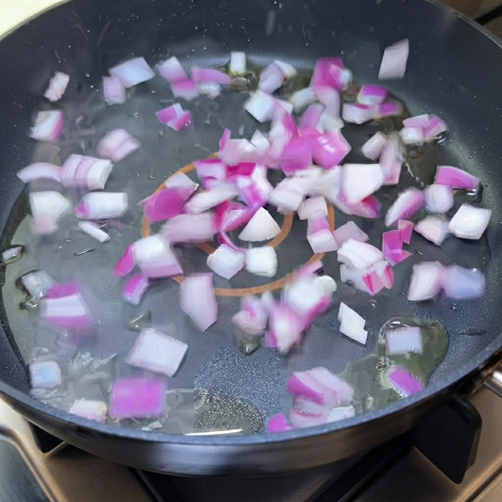 Cebolla morada picada chisporroteando en aceite dentro de una sartén.