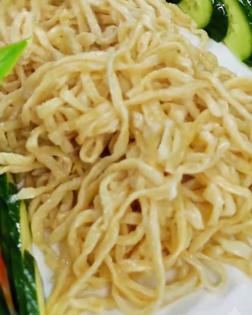 Organizando los trozos de langosta cocidos sobre el lecho de fideos en un plato de servicio blanco.